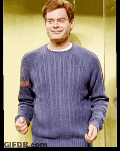 A Man Wearing A Blue Sweater Is Smiling And Making A Funny Face GIF