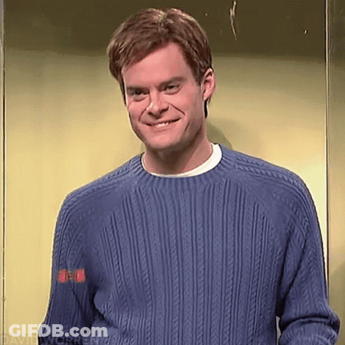 A Man Wearing A Blue Sweater Is Smiling While Standing In An Elevator . GIF