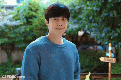 A Man Wearing A Blue Sweater Is Standing In Front Of A Sign That Says ' Shack ' On It . GIF