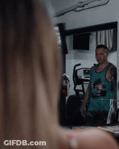 A Man Wearing A Blue Tank Top With Palm Trees On It Looks At Himself In A Mirror GIF