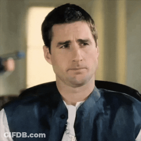 A Man Wearing A Blue Vest And A White Shirt Makes A Sad Face GIF
