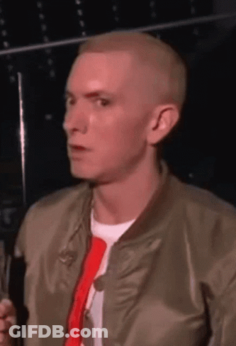 A Man Wearing A Bomber Jacket And A Red Tie Is Talking Into A Microphone GIF