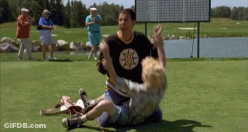 A Man Wearing A Boston Bruins Shirt Is Wrestling A Young Boy On A Golf Course . GIF