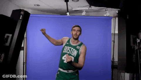 A Man Wearing A Boston Jersey Is Dancing In Front Of A Blue Backdrop GIF