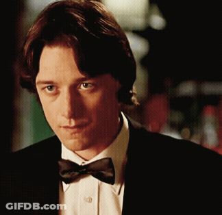 A Man Wearing A Bow Tie And A Suit Looks At The Camera GIF
