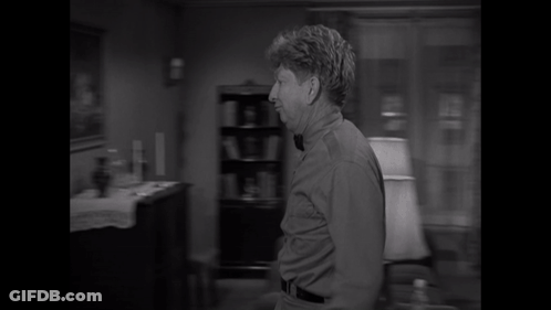 A Man Wearing A Bow Tie Is Standing In A Doorway GIF