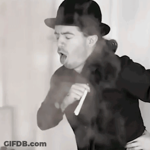 A Man Wearing A Bowler Hat Is Smoking A Cigarette In A Black And White Photo GIF