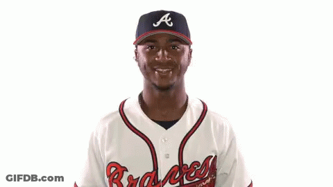 A Man Wearing A Braves Jersey Holds His Arms Up In The Air GIF