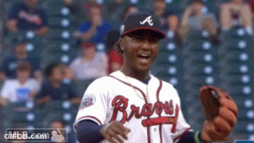 A Man Wearing A Braves Jersey Is Holding A Glove GIF