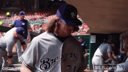 A Man Wearing A Brewers Jersey And A Mlb.com Logo GIF
