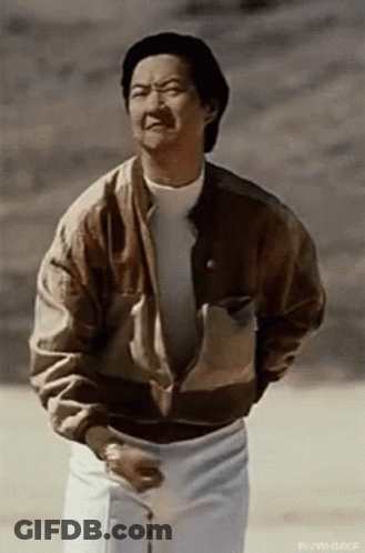 A Man Wearing A Brown Jacket And White Pants Is Standing In The Desert . GIF