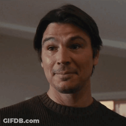 A Man Wearing A Brown Sweater Is Looking At The Camera GIF