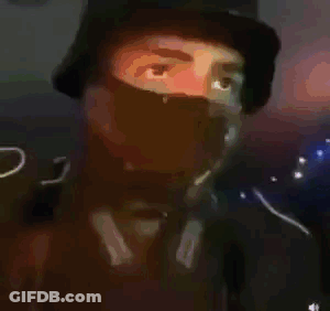 A Man Wearing A Bucket Hat And A Green Mask . GIF