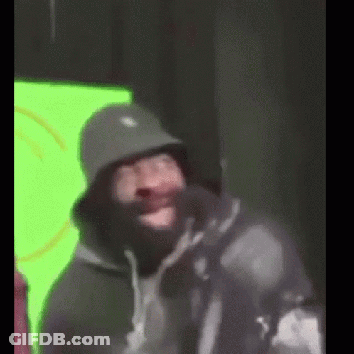A Man Wearing A Bucket Hat And A Mask Is Making A Funny Face . GIF