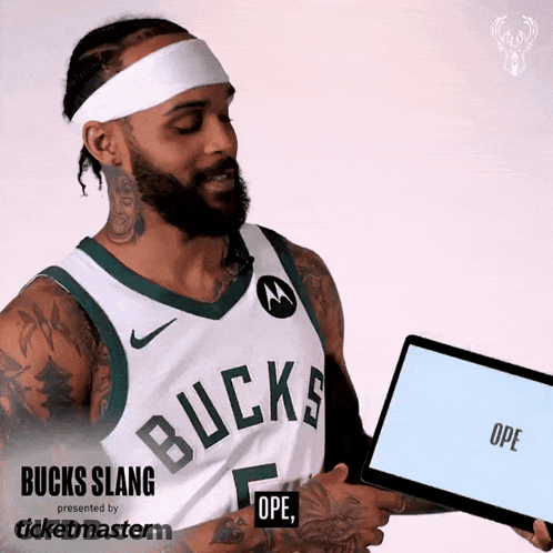 A Man Wearing A Bucks Jersey Is Holding A Tablet GIF