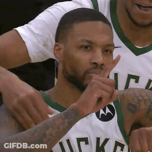 A Man Wearing A Bucks Jersey Is Making A Shhh Gesture GIF