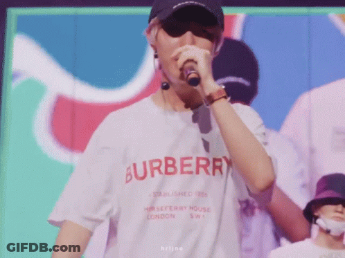A Man Wearing A Burberry Shirt Singing Into A Microphone GIF