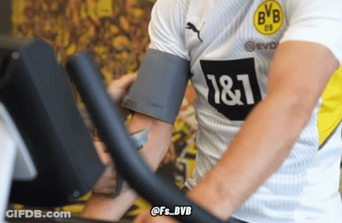 A Man Wearing A Bvb Shirt Rides An Exercise Bike GIF