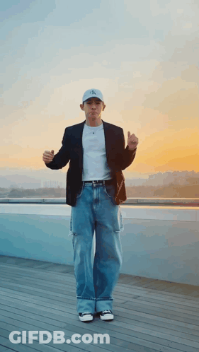 A Man Wearing A Calvin Klein Hat Is Standing On A Balcony GIF