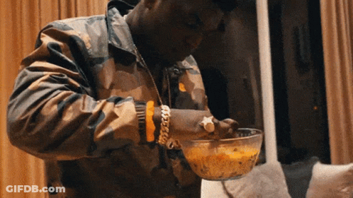 A Man Wearing A Camouflage Jacket Is Eating A Bowl Of Food GIF