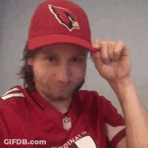 A Man Wearing A Cardinals Hat And A Red Jersey Is Adjusting His Hat . GIF