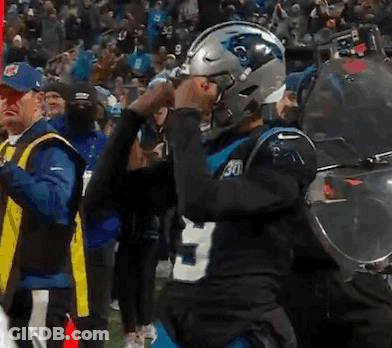A Man Wearing A Carolina Panthers Helmet Stands In Front Of A Crowd . GIF