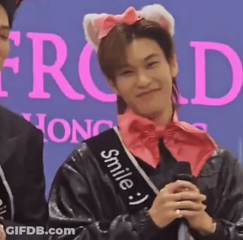 A Man Wearing A Cat Ear Headband And A Sash That Says Smile Is Holding A Microphone And Smiling . GIF