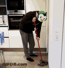 A Man Wearing A Cat Mask Is Mopping The Floor In A Kitchen GIF