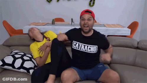 A Man Wearing A Catracha Shirt Sits On A Couch GIF