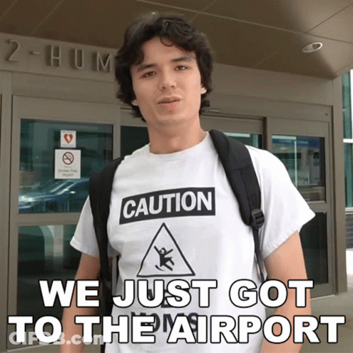 Man In Caution T-Shirt Standing Before Building GIF