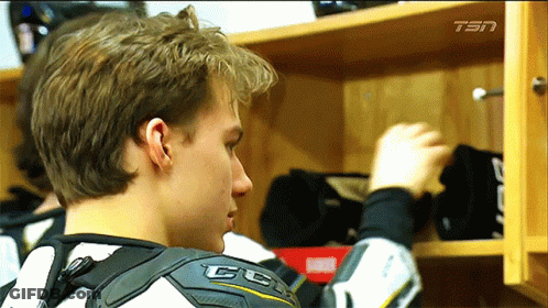 A Man Wearing A Ccm Shoulder Protector Looks Into A Closet GIF