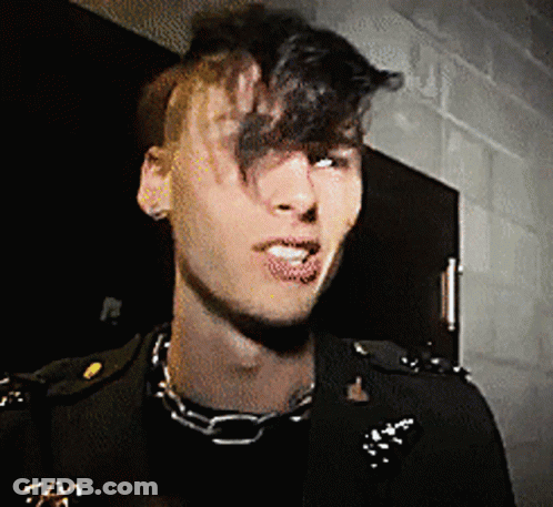 A Man Wearing A Chain Around His Neck And A Black Jacket GIF