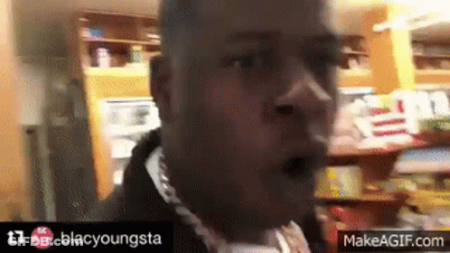 A Man Wearing A Chain Around His Neck Is Making A Funny Face . GIF
