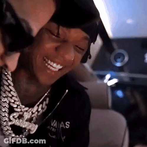 A Man Wearing A Chain Around His Neck Is Smiling While Another Man Looks On . GIF