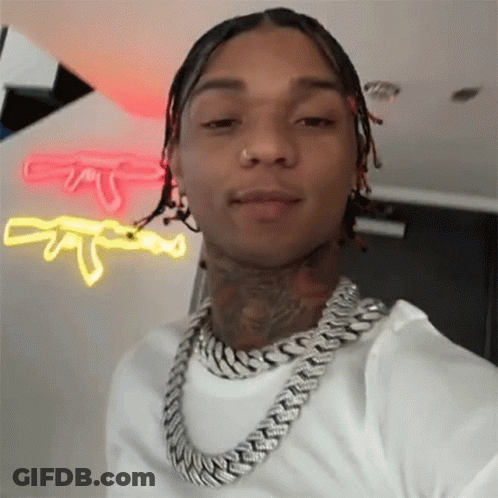 A Man Wearing A Chain Around His Neck Is Taking A Selfie In Front Of A Neon Sign . GIF