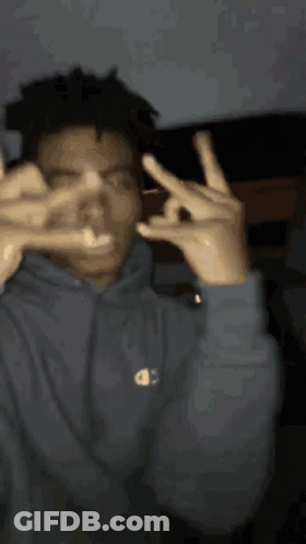 A Man Wearing A Champion Hoodie Is Making A Peace Sign With His Hands GIF