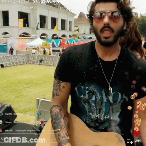 A Man Wearing A Chaos Amiri T-Shirt Is Playing A Guitar GIF