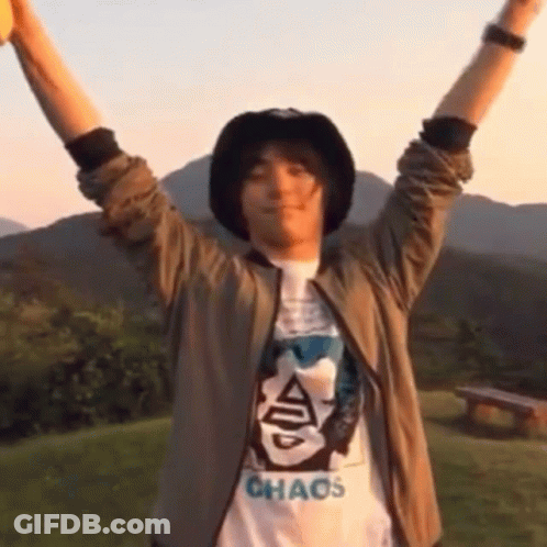 A Man Wearing A Chaos T-Shirt Holds His Arms Up In The Air GIF