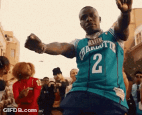A Man Wearing A Charlotte Hornets Jersey Is Dancing In Front Of A Crowd GIF