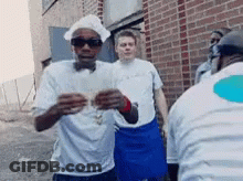 A Man Wearing A Chef 'S Hat And Sunglasses Stands In Front Of A Brick Building GIF