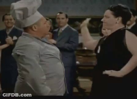 A Man Wearing A Chef 'S Hat Is Dancing With A Woman . GIF