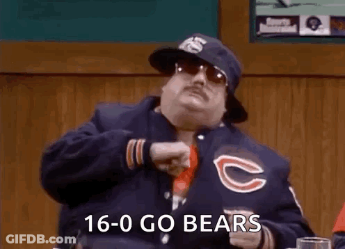 A Man Wearing A Chicago Bears Jacket Is Sitting At A Table In A Bar . GIF
