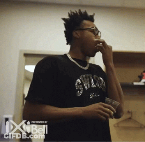 A Man Wearing A Chicago Bulls Shirt Is Drinking From A Cup GIF