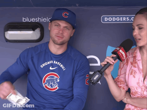 A Man Wearing A Chicago Cubs Shirt Is Being Interviewed By A Woman With A Microphone GIF