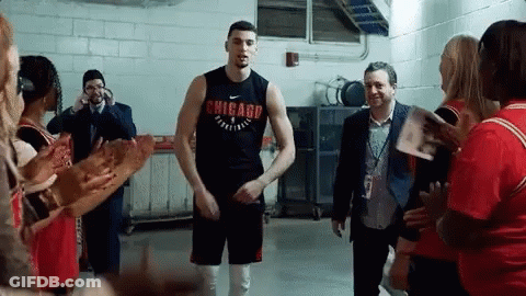 A Man Wearing A Chicago Shirt Stands In A Locker Room Surrounded By People GIF