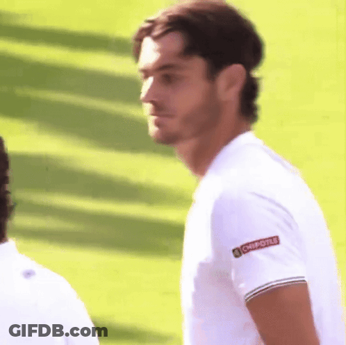 A Man Wearing A Chipotle Shirt Stands On A Lush Green Field GIF