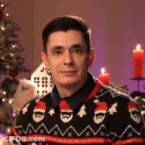 A Man Wearing A Christmas Sweater Has A Santa Hat On GIF