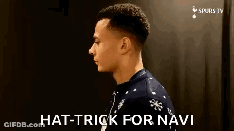 A Man Wearing A Christmas Sweater Is Standing In Front Of A Black Wall And Says `` Hat Trick For Navi '' . GIF