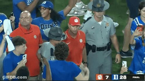 A Man Wearing A Clemson Hat Is Surrounded By Fans And Police Officers GIF