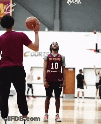 A Man Wearing A Cleveland Jersey Is Throwing A Basketball To Another Man GIF